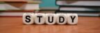 Close-up of study blocks and stacked books on a wooden desk, symbolizing education and learning.